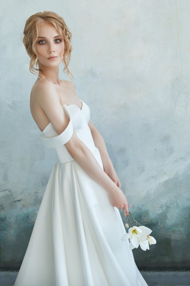 woman in elegant dress looking at camera with flower