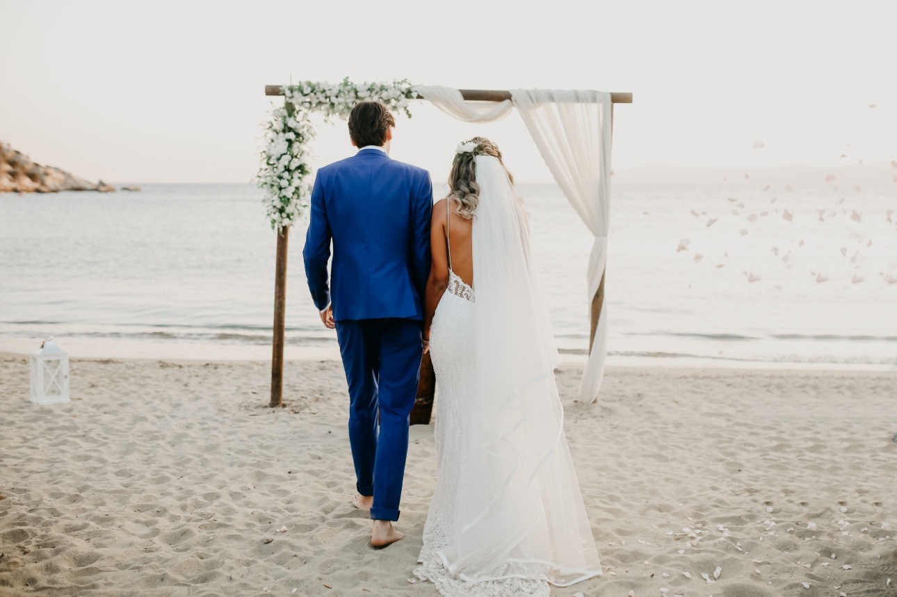 bride and groom tying the knot on the beach with frame for ceremony