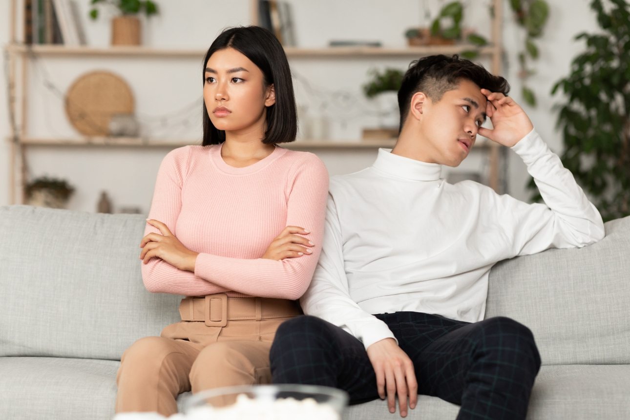 couple sitting back to back unhappy on sofa