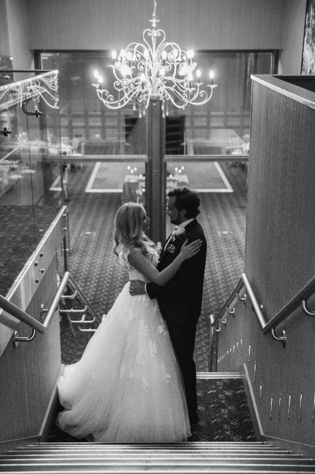 couple standing on stairs below chandelier
