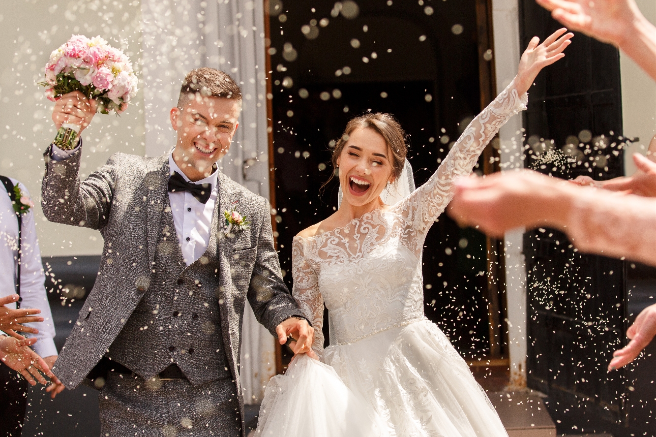 bride and groom leaving church under a shower of confetti
