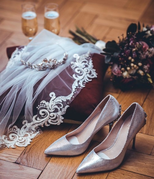 a collection of wedding accessories on a floor such as shoes tiara flowers