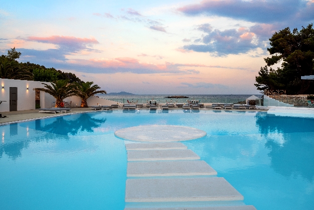 hotel pool at night with stepping stones in the water and sea views