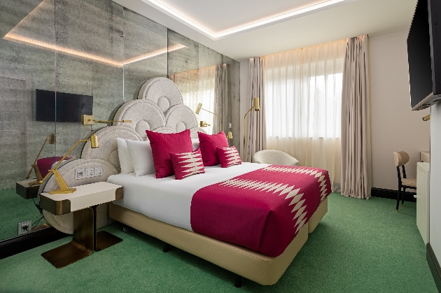 1940s style bedroom with green carpets, striking headbord and pink bedsheets