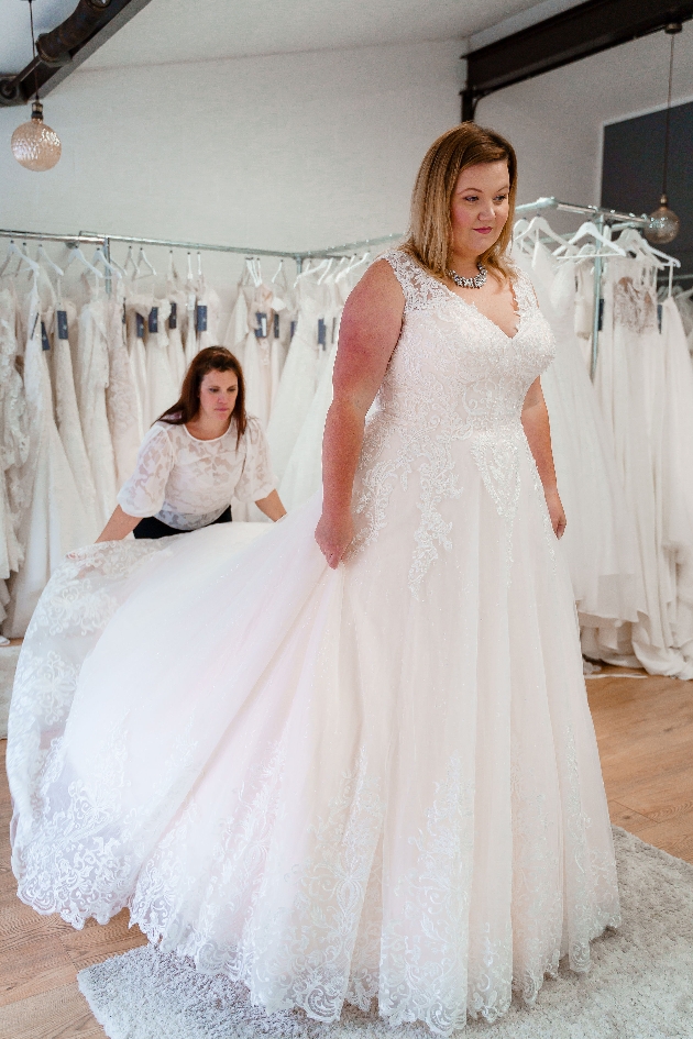 woman in wedding dress being helped by a sales assitant