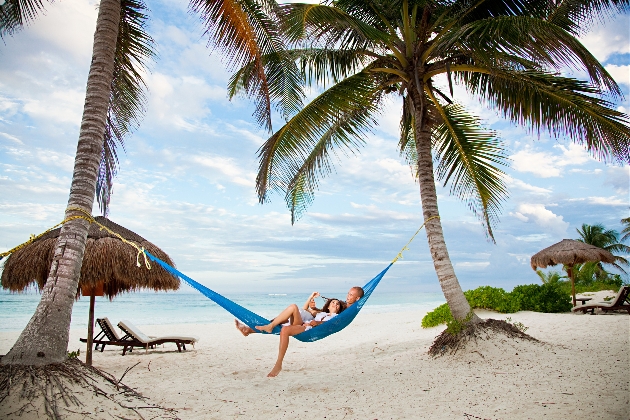 Honeymoon couple in a hammock on a beach with palm trees