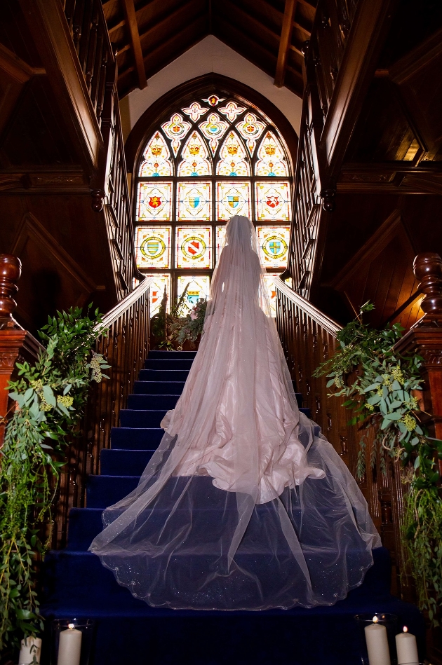 bride standing on a wooden staircase with stain glass window