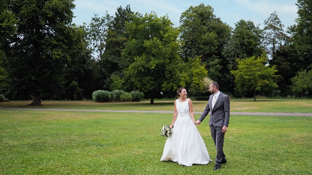 bride and groom walking hand in hand across the lawn