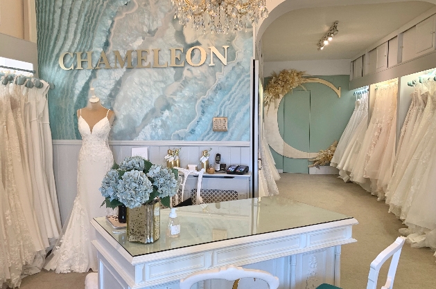 interior of boutique all white with blue touches dresses hanging on rails
