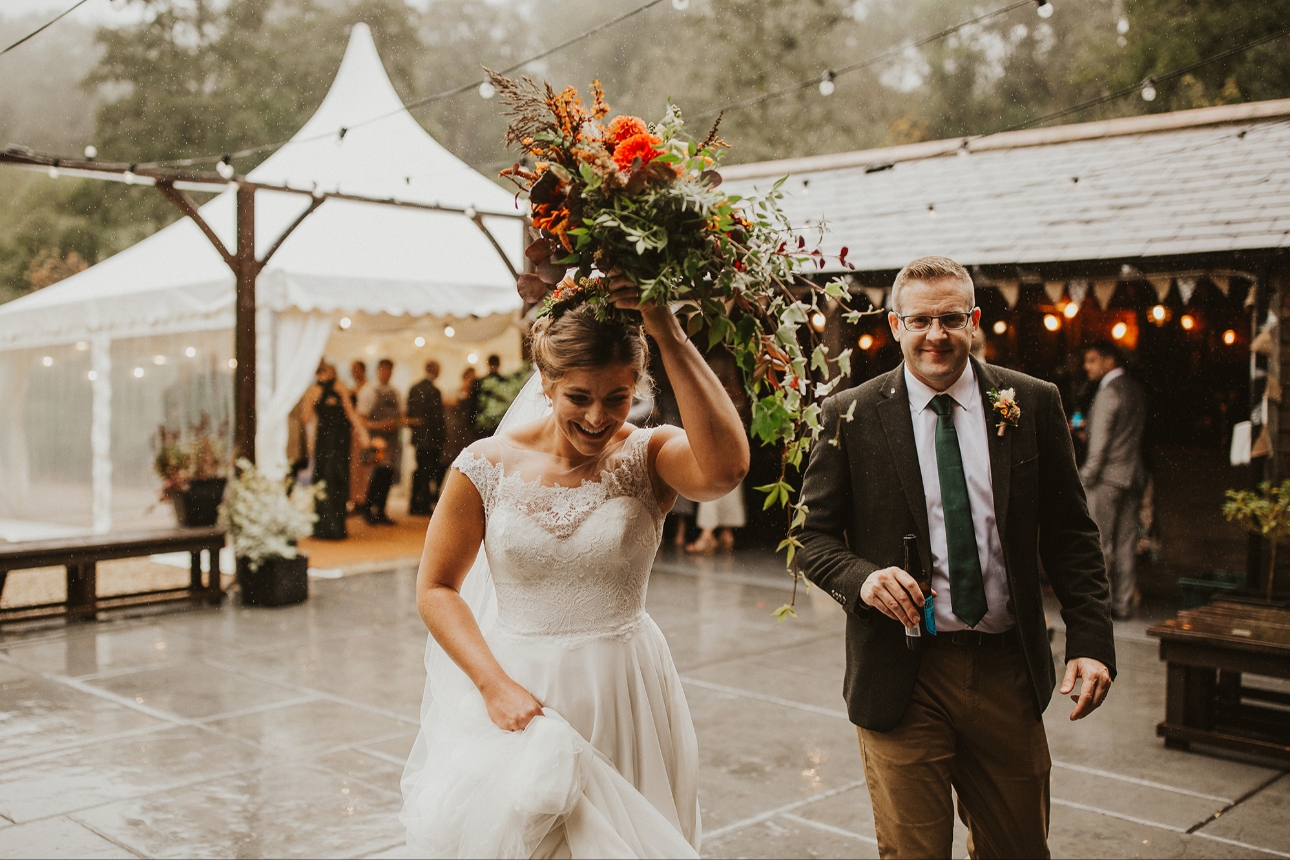 Bride shelters from rain with bouquet