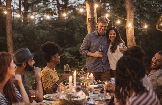 men and women sitting at a table outside having dinner