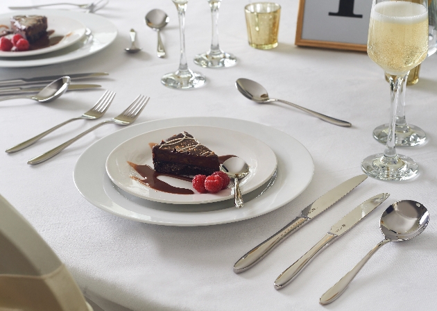 cutlery set on a table laid out for a piece of cake on a plate