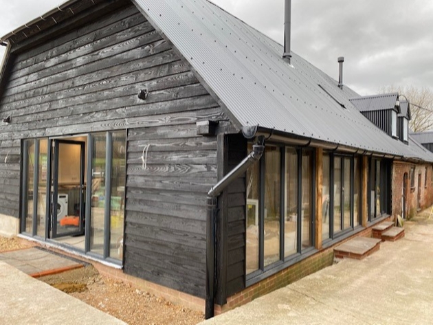 black wooden building with floor to ceiling bi fold doors and windows