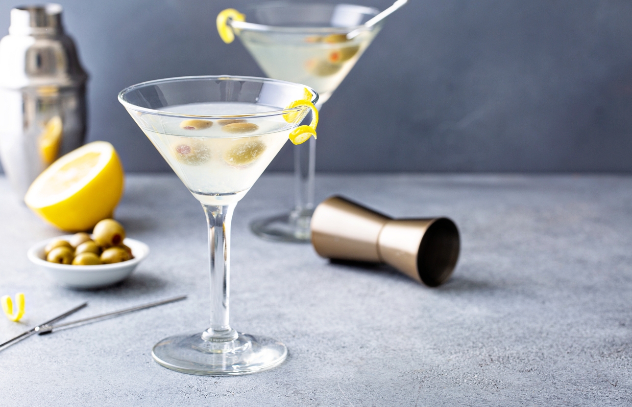 Martini cocktail in a glass with olives and lemon on the side