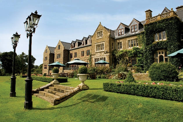 yellow stone historic manor covered in ivy with steps down to lawned area