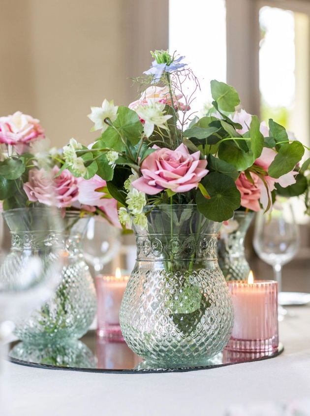 small vase of flowers on glass mirror