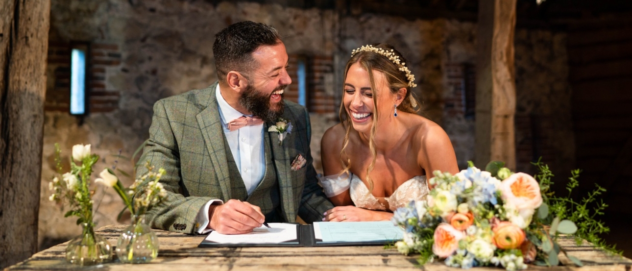 Couple laugh as they sign the register