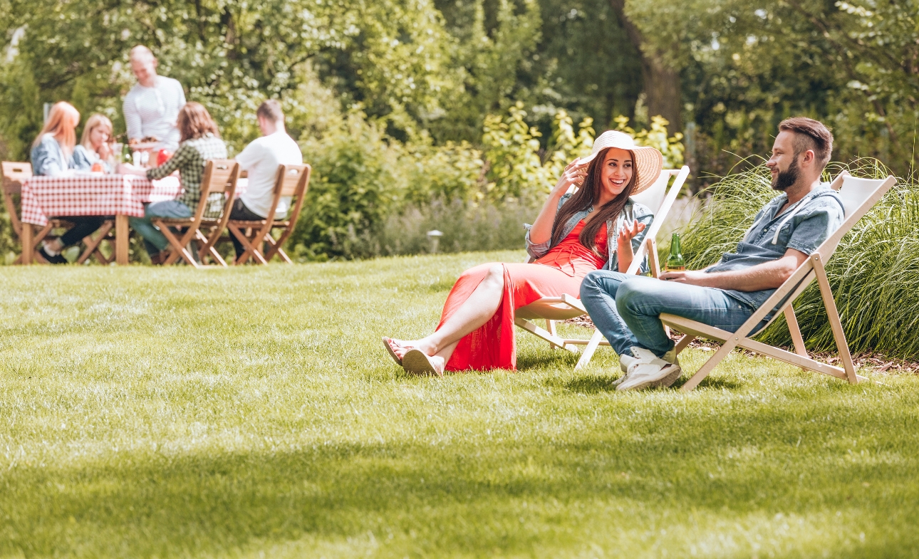 man and woman in deck chairs in the sunshine on a green lawn