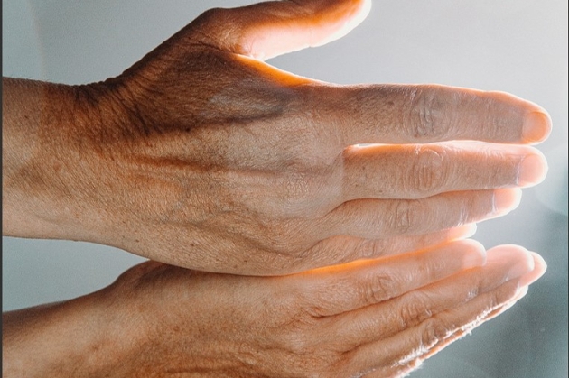 Hands in sunlight with a grey backing. 