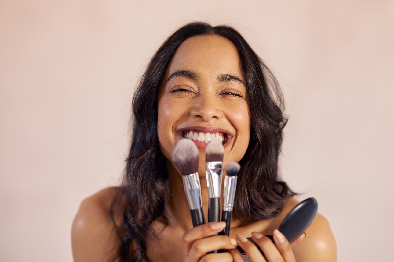 woman's face with her holding make-up brushes in front of her