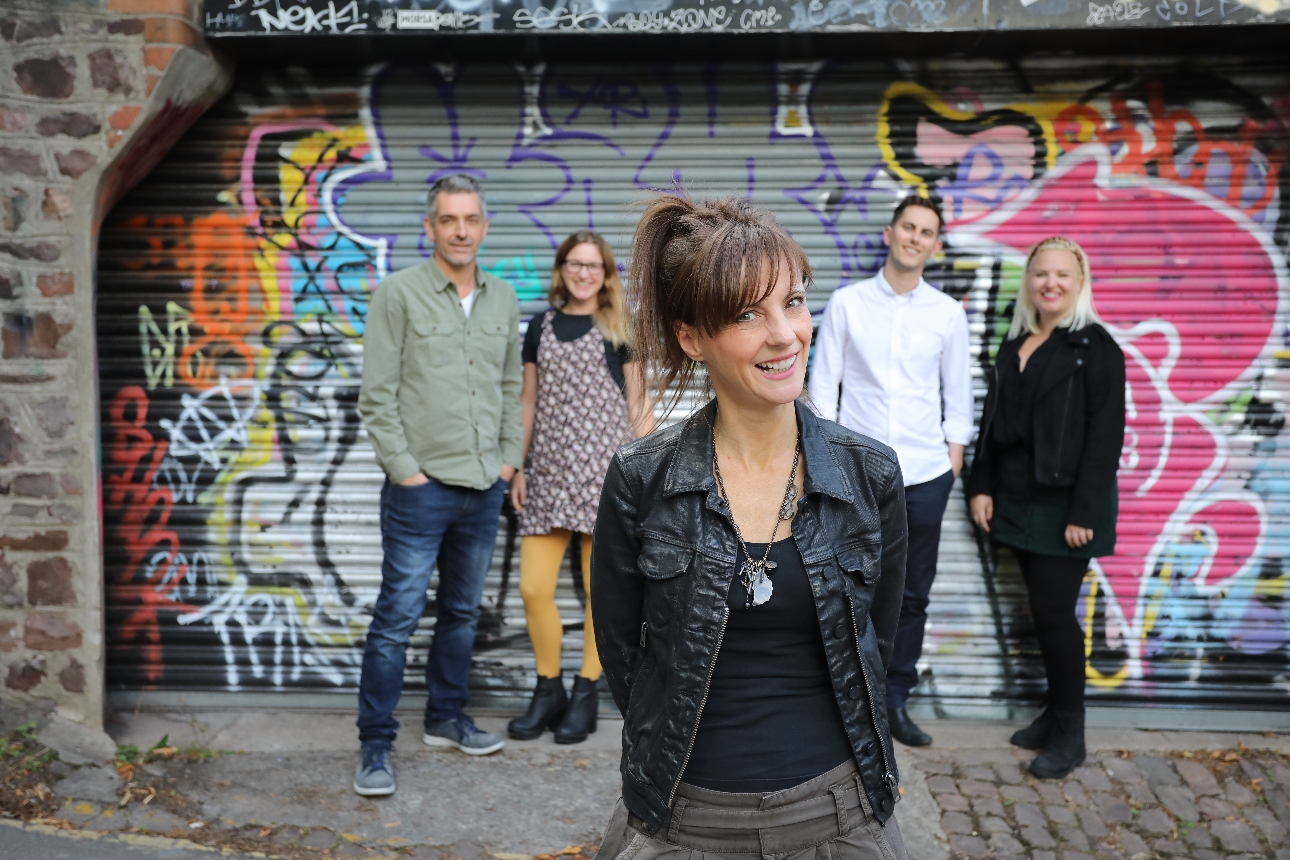 group of people standing in front of graffiti painted shutter