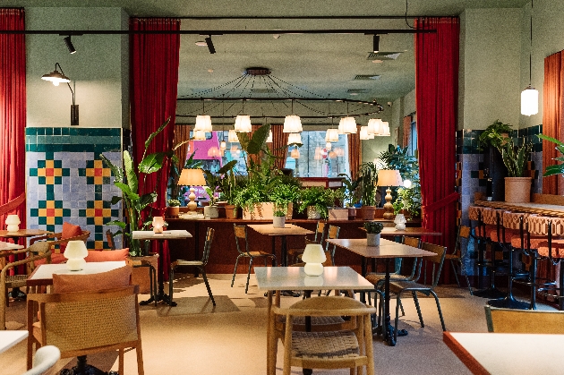 A dining room decorated with plants and red curtains