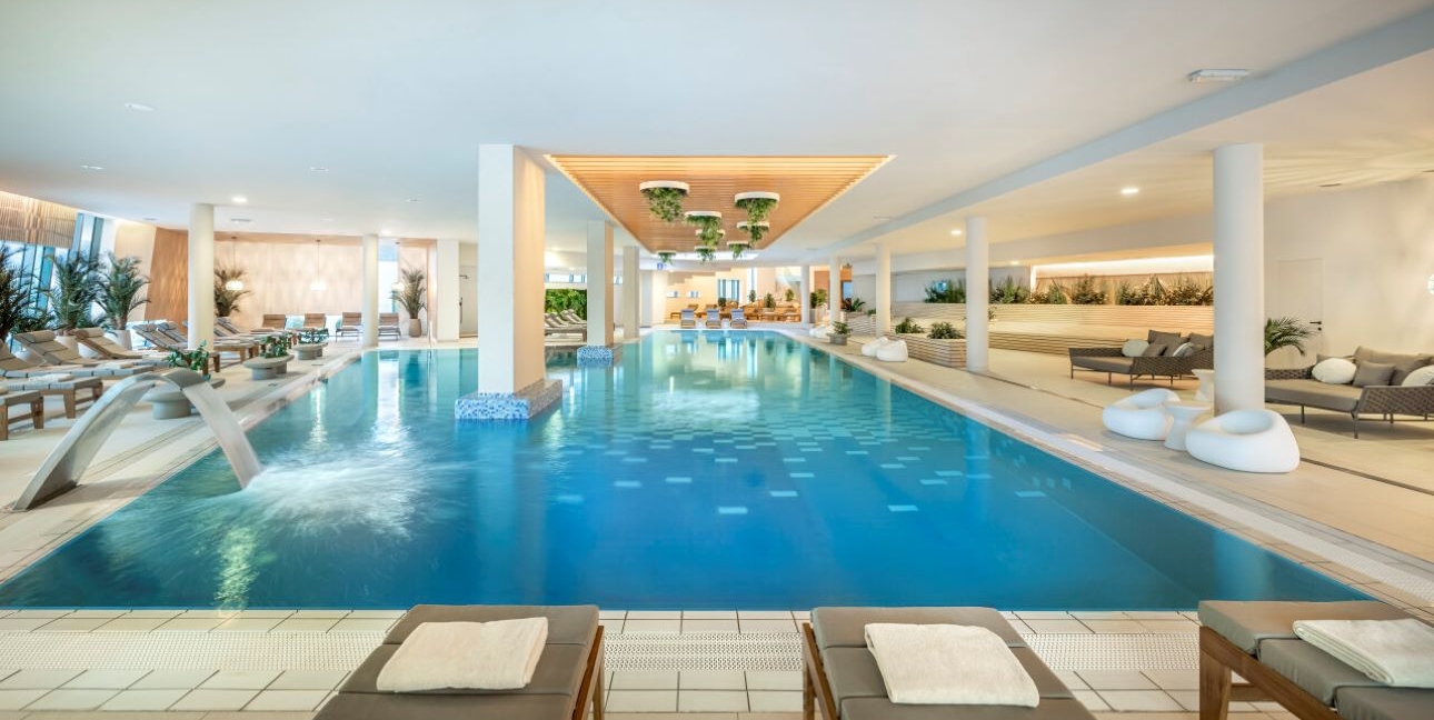 pool in spa area with sofas and loungers around it 