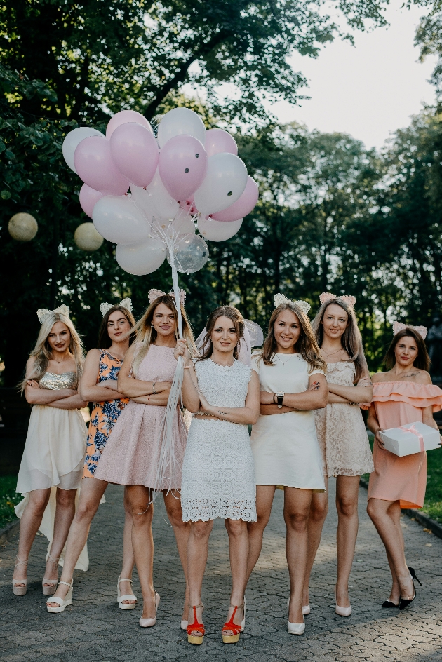 group of women in partywear holding balloons outside