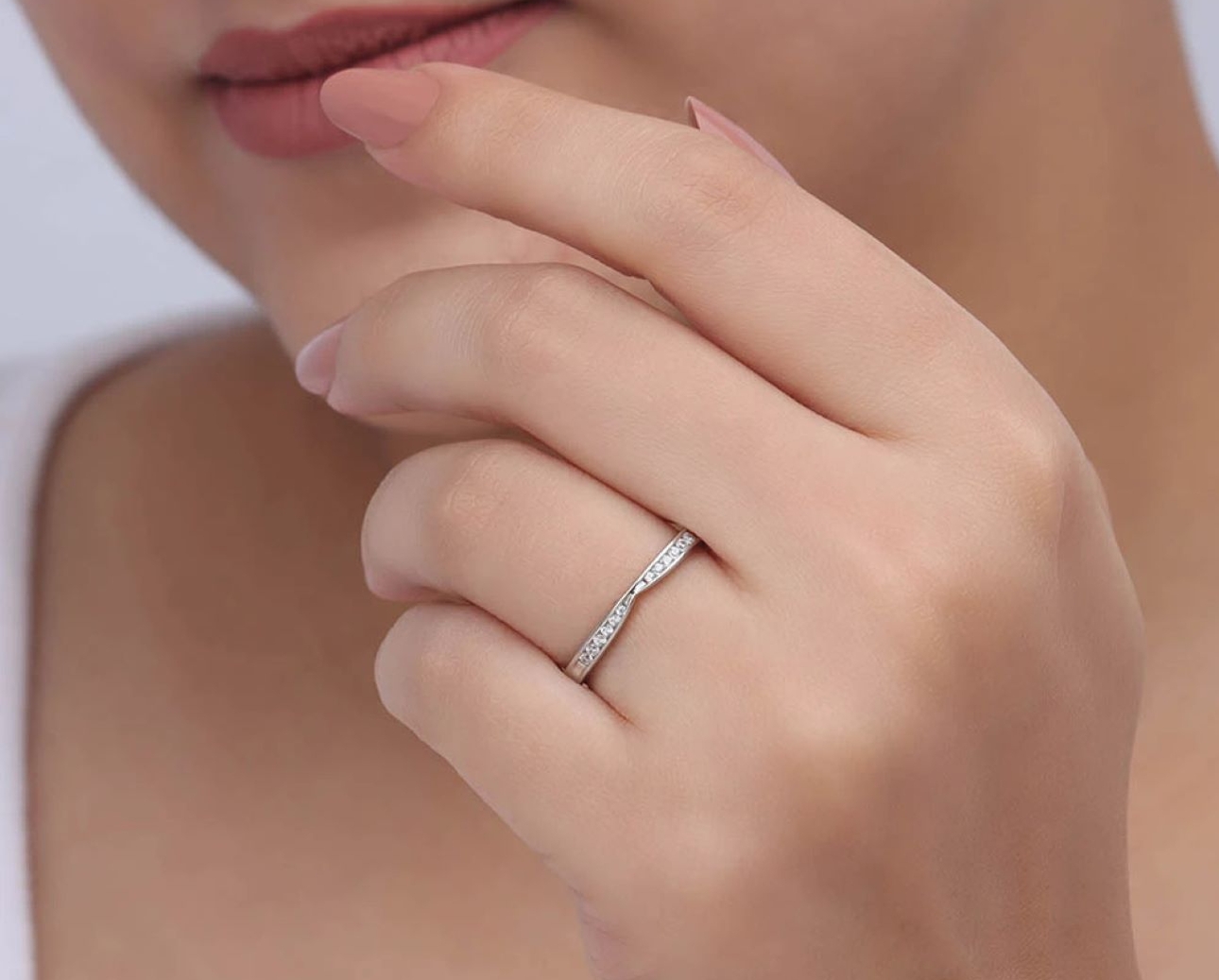 woman's hand with wedding band on it raising hand to her face