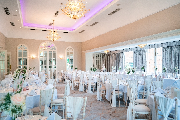 reception room with chivari chairs and table set up for reception chandeliers on ceiling