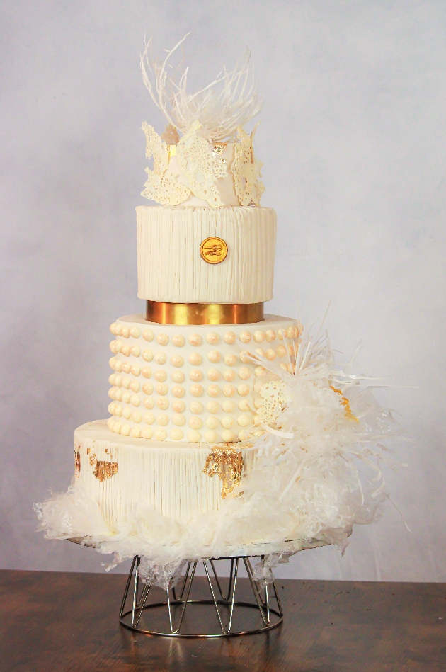 white four tier cake in cream, with gold detail, feather look