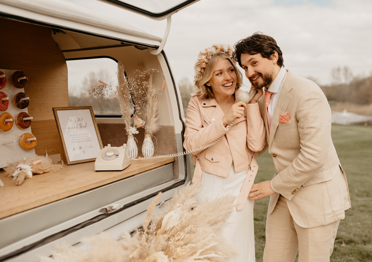 couple talking in to old phone on wedding day out of campervan