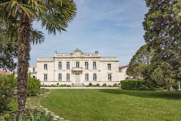 A large white building surrounded by green grass and trees