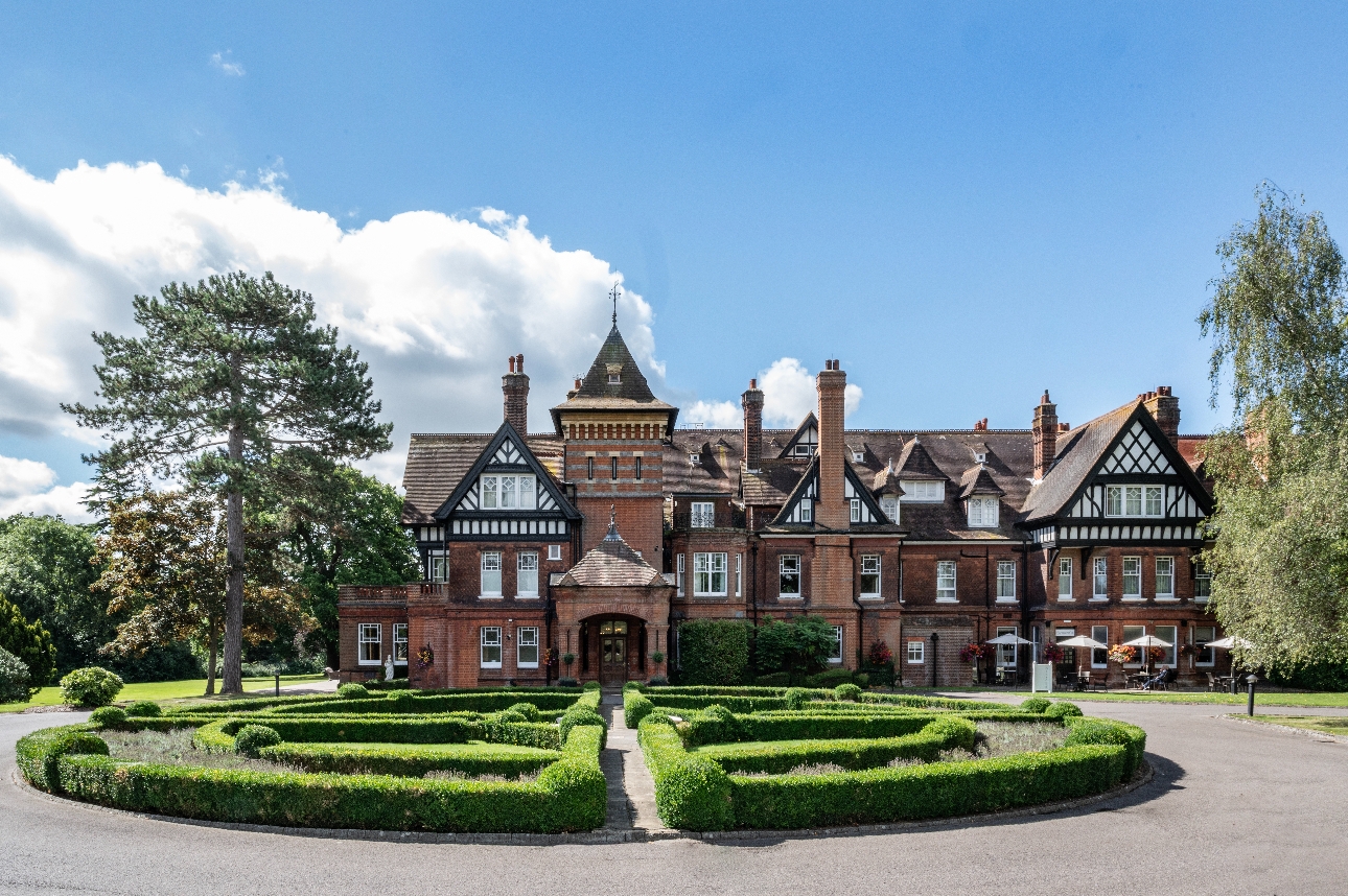 historic manor house with red brick facade and white and black tudor details