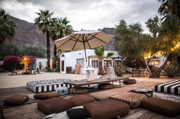 An outdoor seating area with cushions and a white building in the background