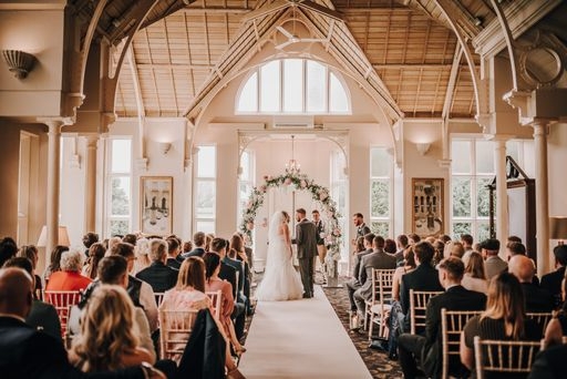 couple at the ceremony in room with high wooden roof and their guests looking on