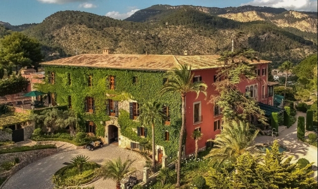 A moss covered large building surrounded by mountains and gardens