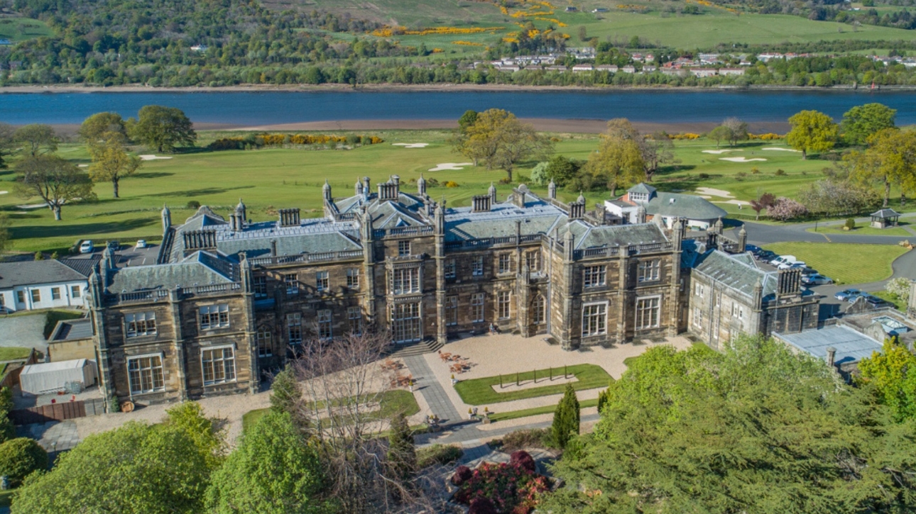 Large hall on expansive green lands with water in the background