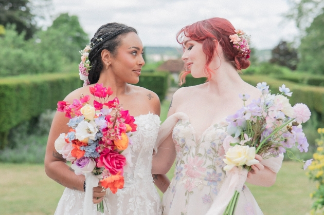 Same-sex couple poses at Hampshire Wedding Network styled shoot with wisteria walk, Figaro car, and sustainable décor.