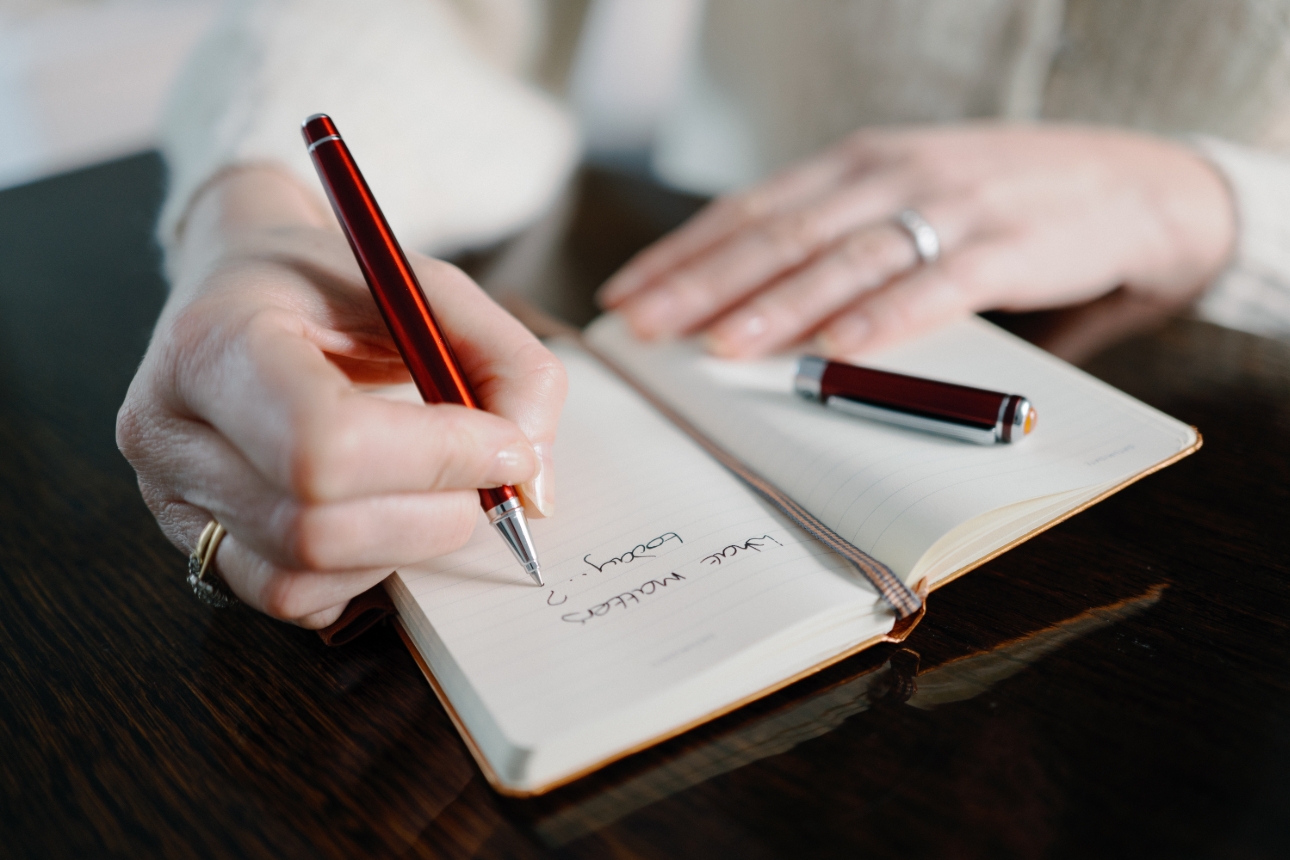 person signing in a book with red pen