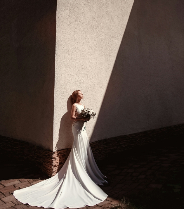bride standing in the sunlight in front of a wall